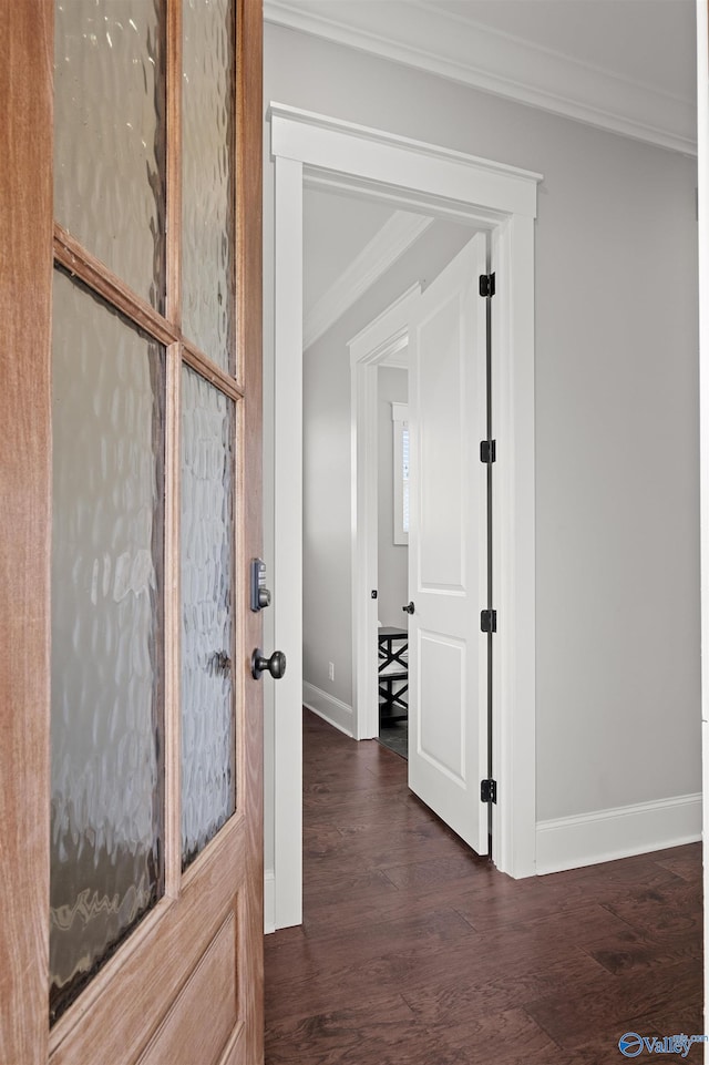 corridor featuring ornamental molding, baseboards, and wood finished floors