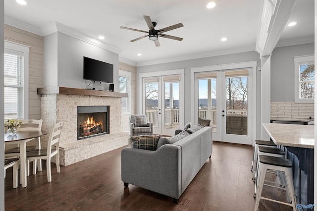 living area featuring dark wood-style floors, french doors, a brick fireplace, and crown molding