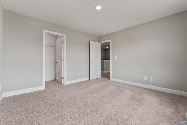 unfurnished bedroom featuring light carpet, a spacious closet, and a closet