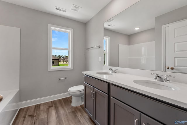 full bathroom with hardwood / wood-style floors, shower / washtub combination, toilet, and double vanity