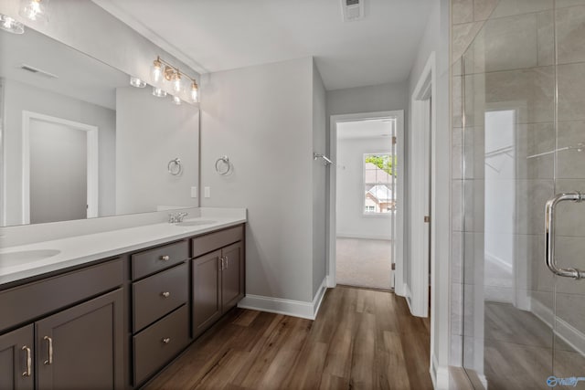 bathroom featuring hardwood / wood-style floors, double vanity, and an enclosed shower