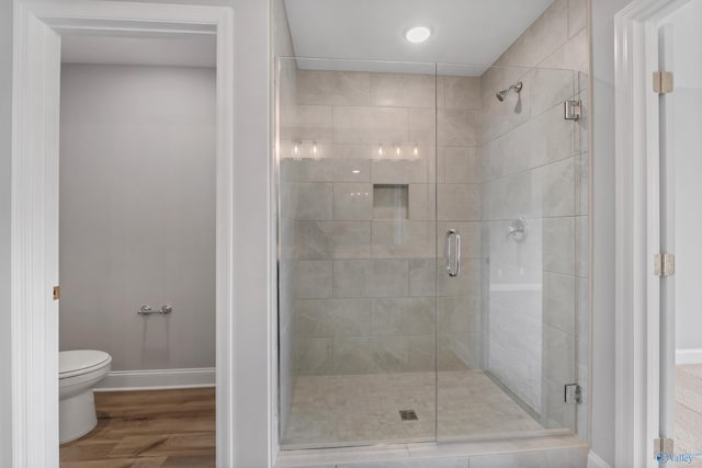 bathroom with hardwood / wood-style flooring, toilet, and a shower with shower door