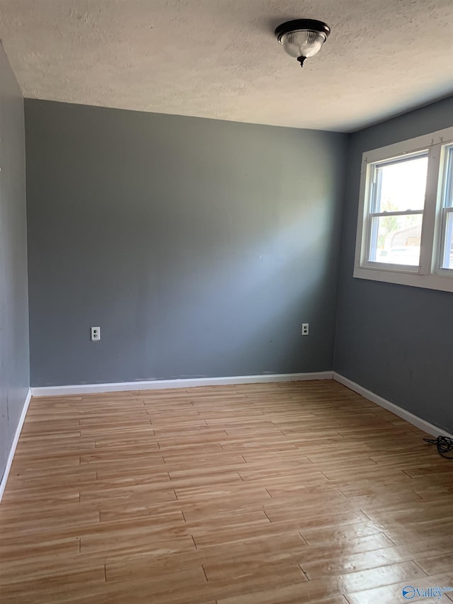 empty room featuring a textured ceiling and light hardwood / wood-style flooring