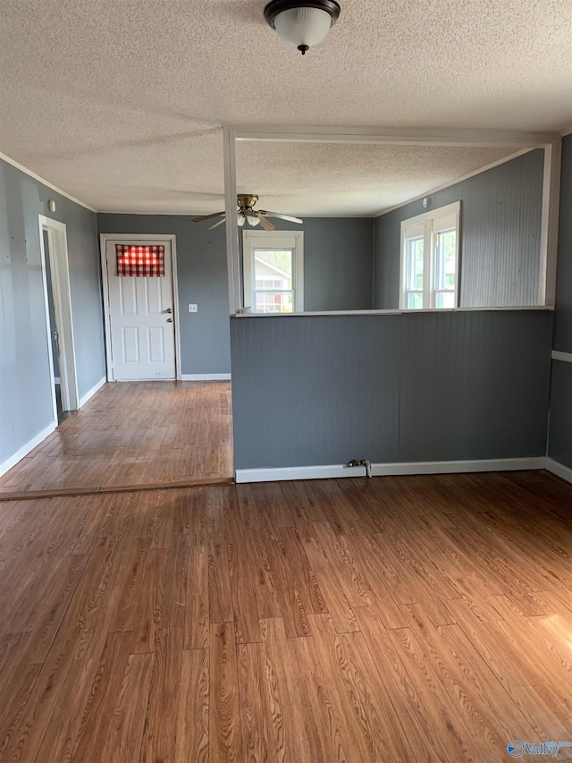 spare room with ceiling fan, wood walls, wood-type flooring, and a textured ceiling