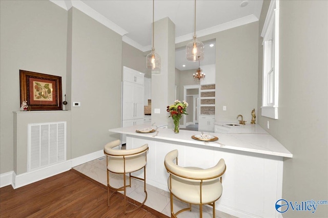 kitchen with sink, hanging light fixtures, dark hardwood / wood-style floors, light stone countertops, and kitchen peninsula