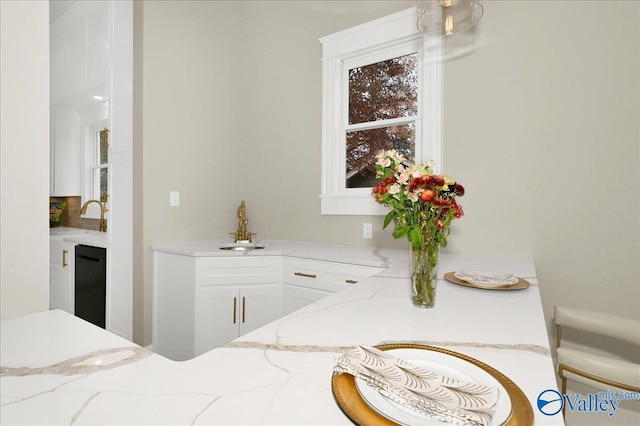 bar featuring white cabinets, dishwasher, light stone countertops, and sink