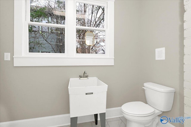 bathroom with tile patterned flooring, toilet, a healthy amount of sunlight, and sink