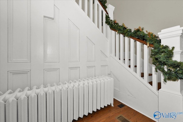 stairs featuring wood-type flooring and radiator