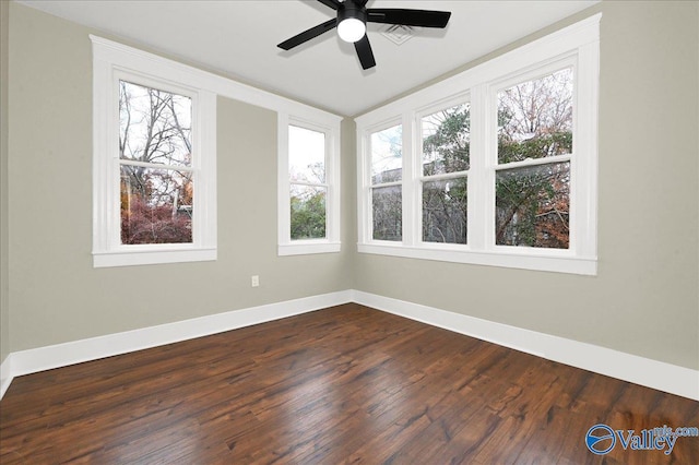 empty room featuring dark hardwood / wood-style flooring, a wealth of natural light, and ceiling fan