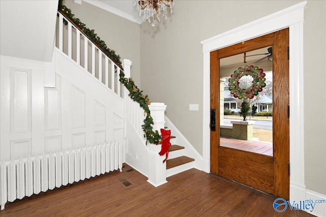 entryway featuring radiator heating unit, an inviting chandelier, dark wood-type flooring, and crown molding