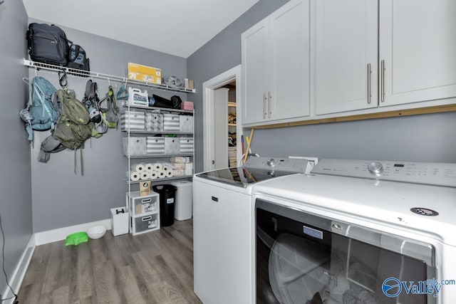 laundry room featuring wood finished floors, washing machine and clothes dryer, cabinet space, and baseboards