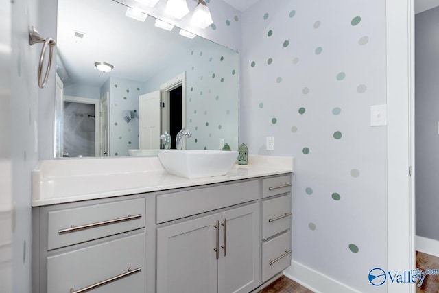 bathroom with baseboards, visible vents, vanity, and wallpapered walls