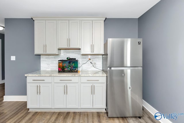 kitchen featuring light stone countertops, backsplash, and freestanding refrigerator