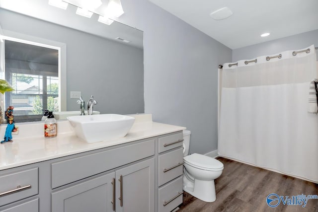 bathroom featuring visible vents, a shower with shower curtain, toilet, vanity, and wood finished floors