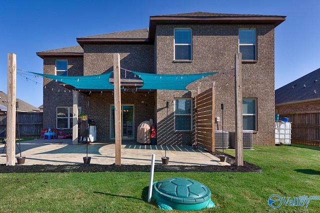 rear view of property with brick siding, a lawn, a patio area, and fence