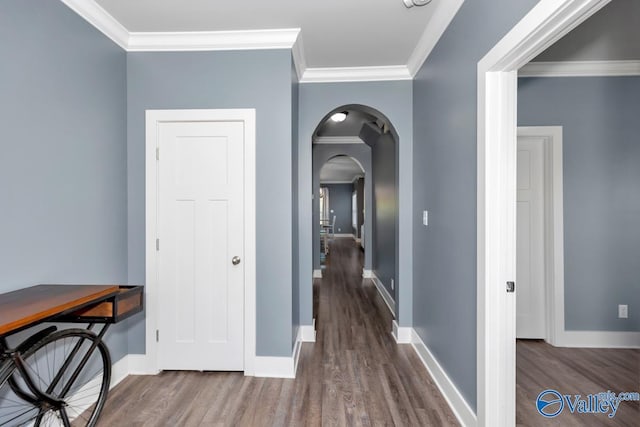 hallway featuring arched walkways, crown molding, and wood finished floors