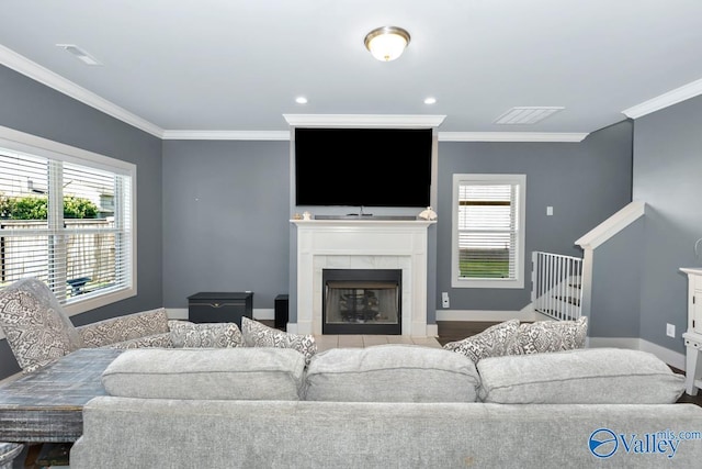 living room with ornamental molding, a tile fireplace, visible vents, and baseboards