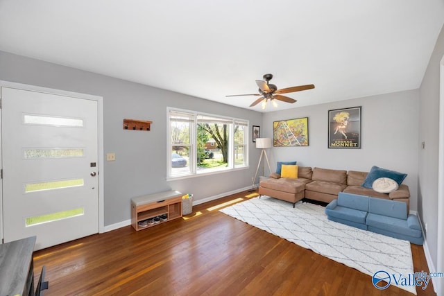 living area with wood finished floors, a ceiling fan, and baseboards