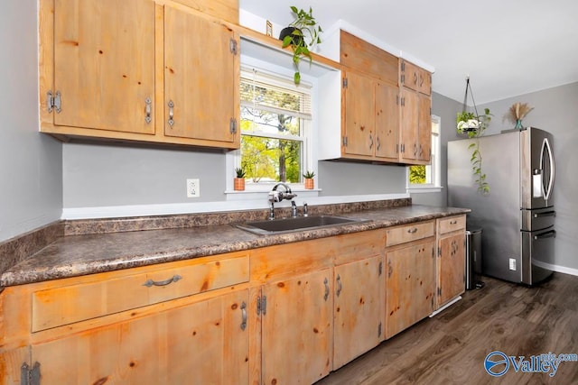 kitchen with a sink, a healthy amount of sunlight, dark countertops, stainless steel refrigerator with ice dispenser, and dark wood-type flooring