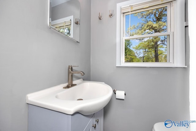 bathroom featuring toilet, vanity, and plenty of natural light