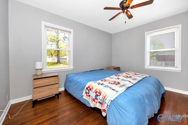 bedroom featuring baseboards, wood finished floors, ceiling fan, and multiple windows