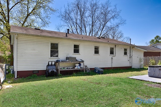 back of property with fence, crawl space, and a lawn
