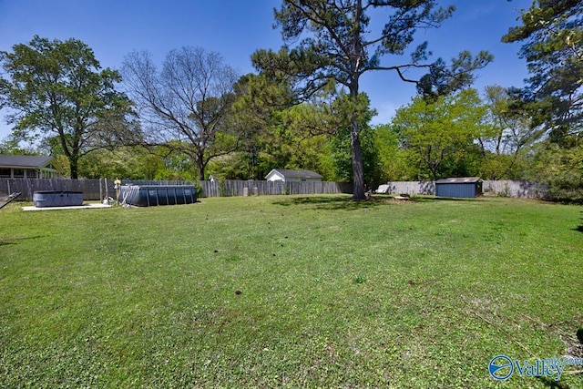 view of yard featuring an outdoor structure, a storage unit, a fenced backyard, and a swimming pool