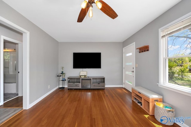 living room featuring baseboards, wood finished floors, and ceiling fan