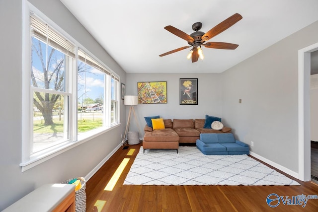 living area with light wood-style flooring, baseboards, and ceiling fan