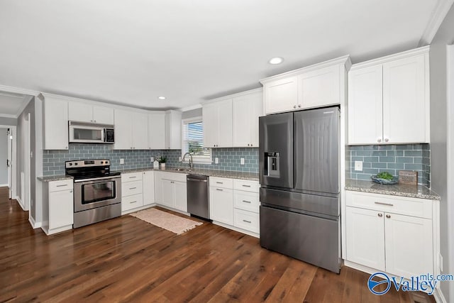 kitchen with stainless steel appliances, a sink, dark wood finished floors, and white cabinetry