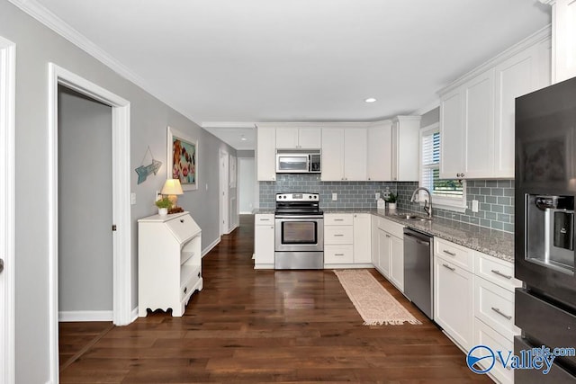 kitchen with light stone counters, stainless steel appliances, a sink, white cabinets, and dark wood finished floors