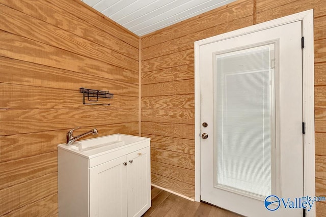 bathroom featuring wood walls, a sink, and wood finished floors