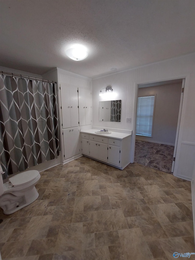 bathroom with vanity, toilet, and a textured ceiling