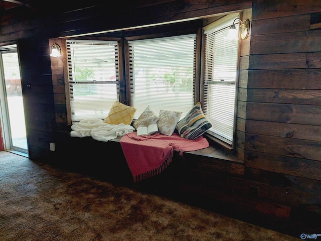 bedroom with carpet flooring, wooden walls, and access to outside