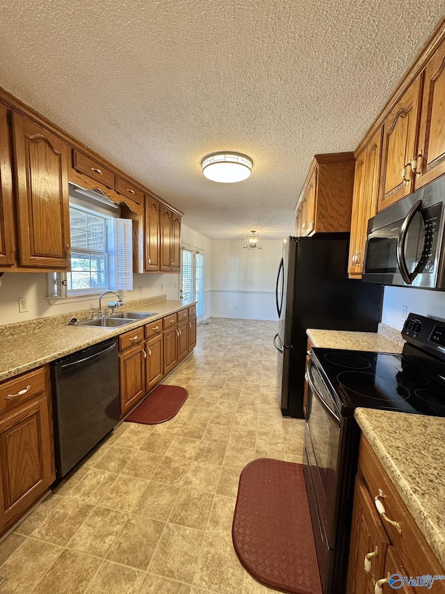 kitchen with a textured ceiling, light stone countertops, sink, and black appliances