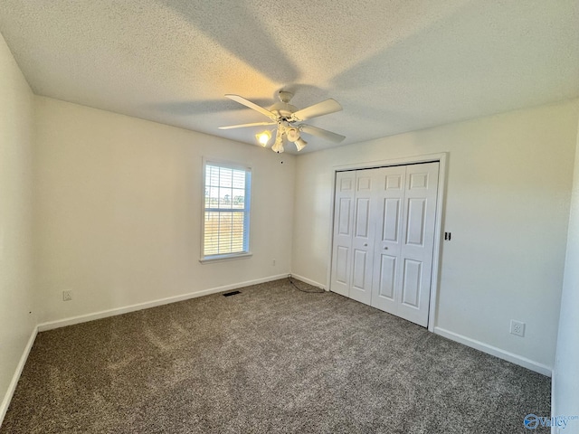 unfurnished bedroom with a textured ceiling, ceiling fan, a closet, and dark colored carpet