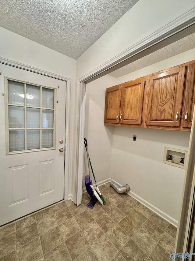 laundry room with electric dryer hookup, washer hookup, a textured ceiling, and cabinets