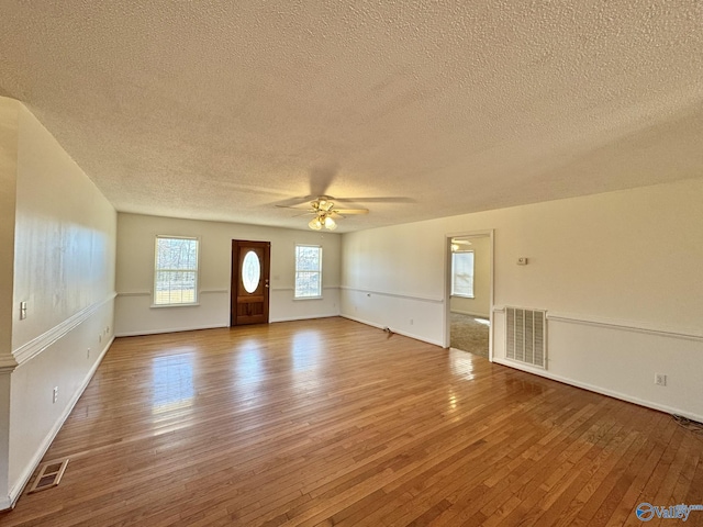 unfurnished living room featuring ceiling fan, wood-type flooring, and a textured ceiling