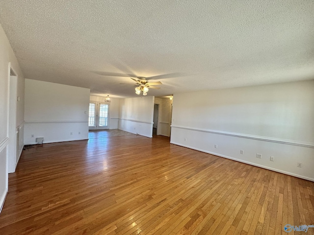 unfurnished room with ceiling fan, wood-type flooring, and a textured ceiling