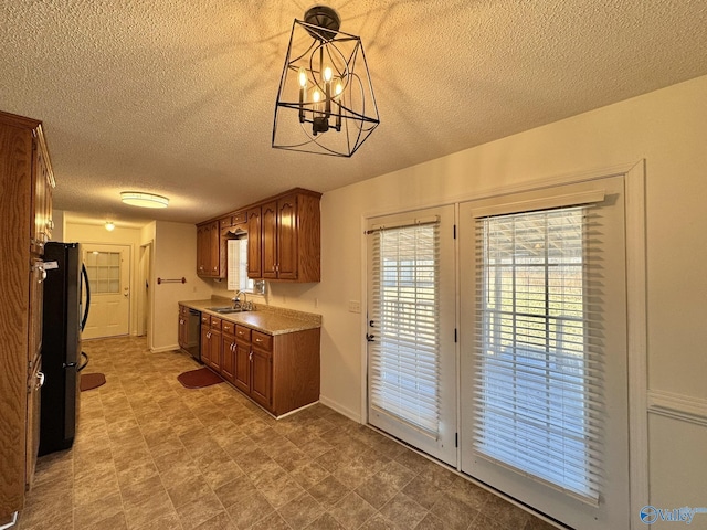 kitchen featuring decorative light fixtures, sink, a textured ceiling, a chandelier, and black appliances