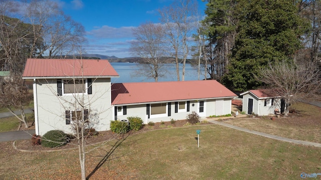 view of front of home with a front yard, a water view, and a shed