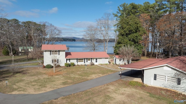 view of front of house with a front yard, a water view, and a carport