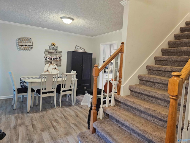 dining area featuring ornamental molding, a textured ceiling, and hardwood / wood-style flooring