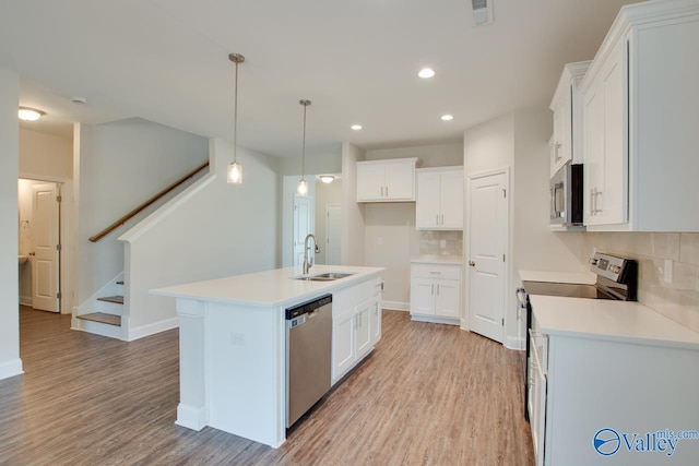 kitchen featuring a kitchen island with sink, sink, stainless steel appliances, and white cabinetry