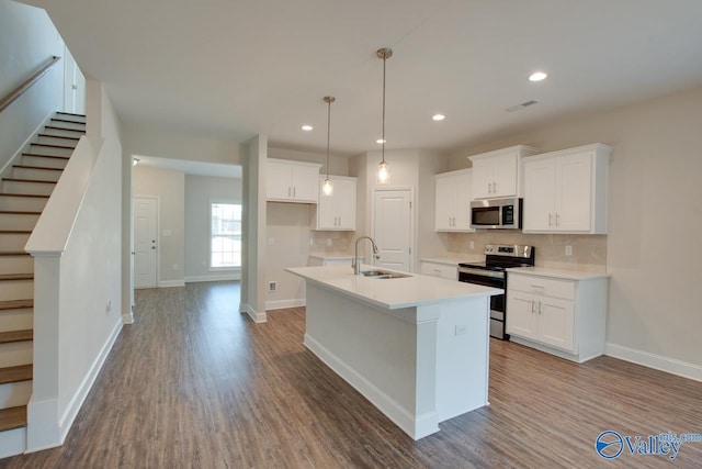 kitchen featuring white cabinets, sink, stainless steel appliances, and a center island with sink