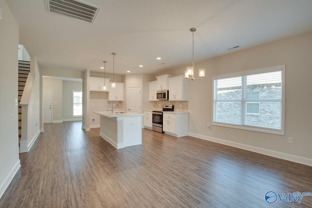 kitchen featuring sink, hanging light fixtures, a kitchen island with sink, stainless steel appliances, and white cabinets