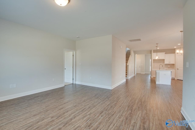 unfurnished living room featuring light wood-type flooring and sink