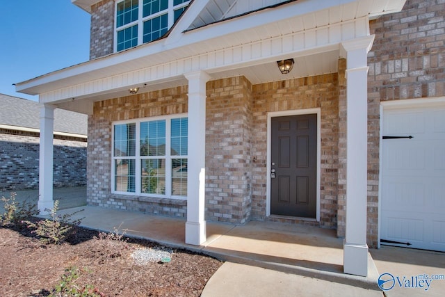 view of exterior entry with covered porch and a garage