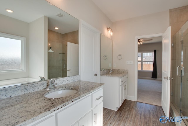 bathroom with ceiling fan, hardwood / wood-style floors, a shower with door, and vanity