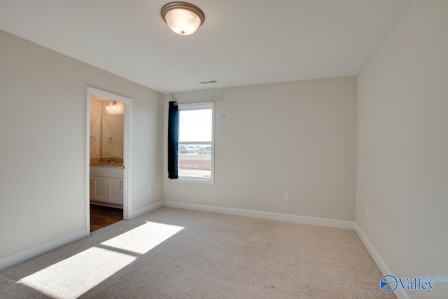 unfurnished bedroom featuring dark colored carpet and ensuite bath